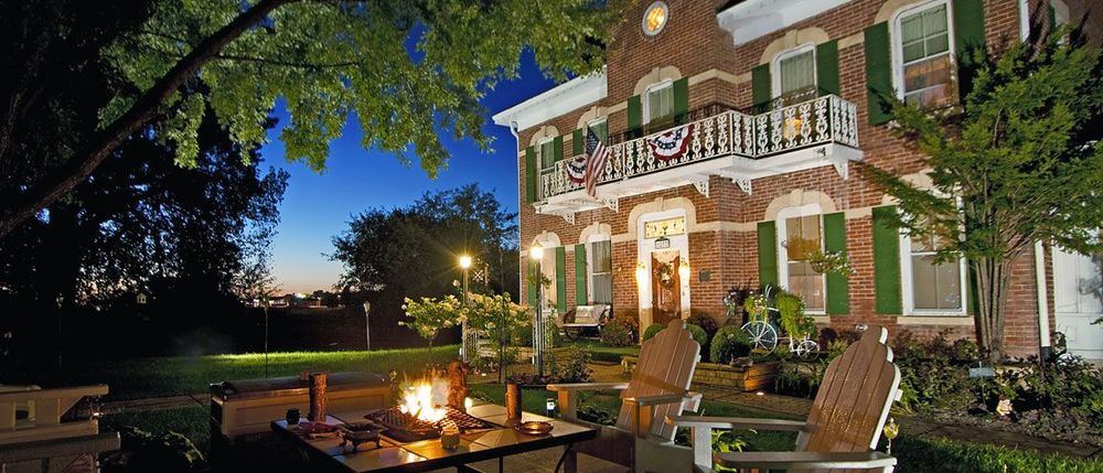 Cloran Mansion glowing at night with the fire pit lit